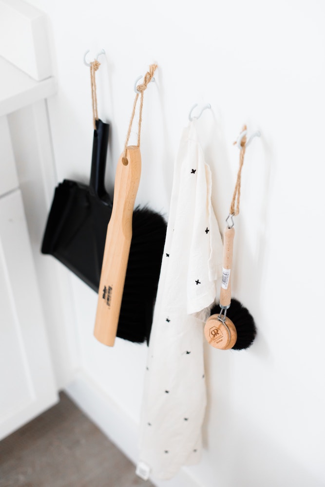 assorted cleaning brushes and cloth hanging in white room