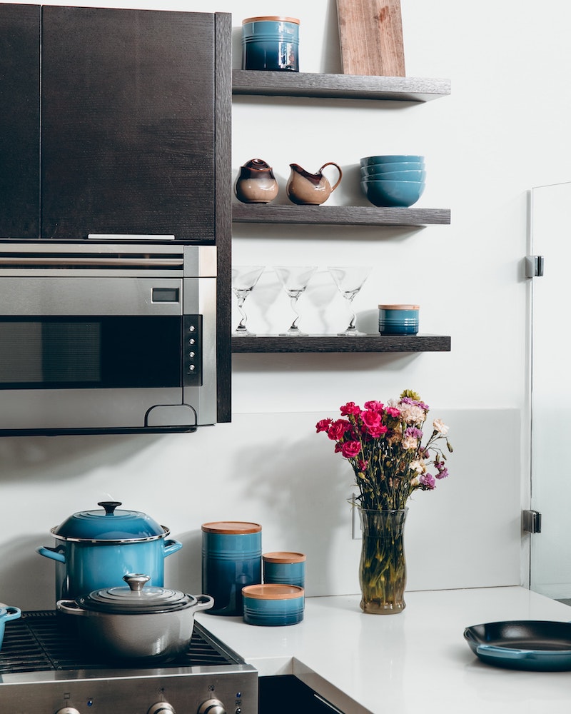 clean kitchen with dark upper cabinets and pink flowers on counter