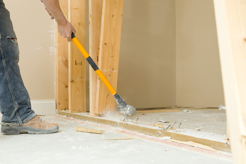 Construction worker tearing down wall with sledgehammer