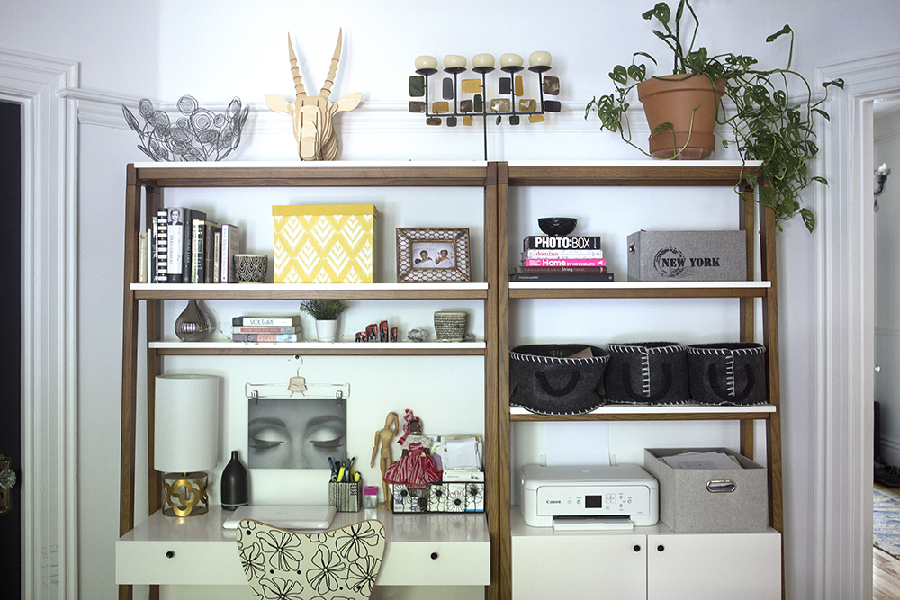 white home office space with decor and books on shelves above desk