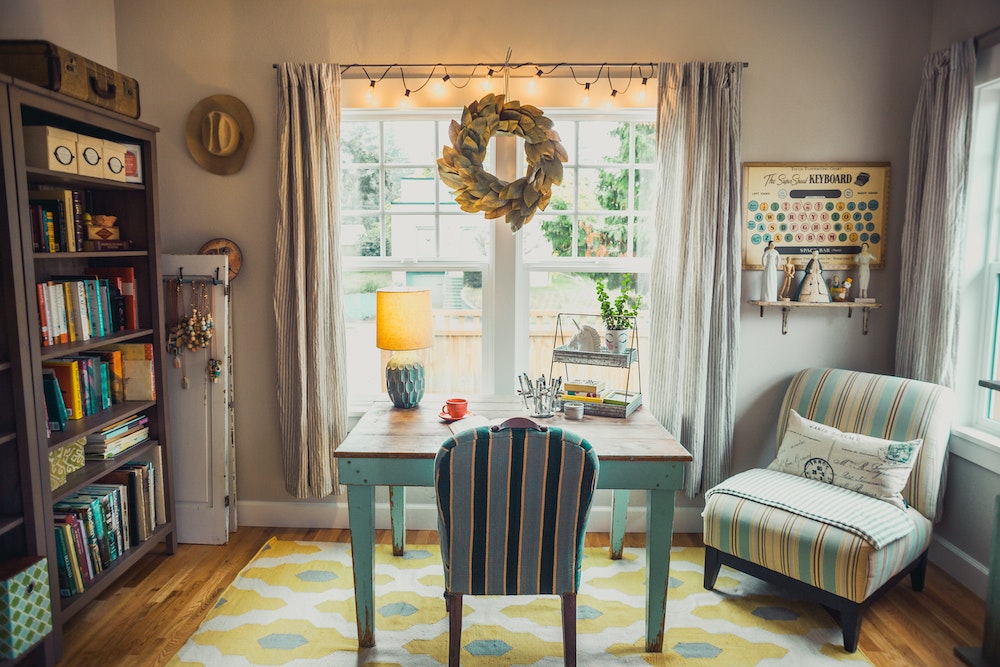 cozy home office with string lights on window in front of desk