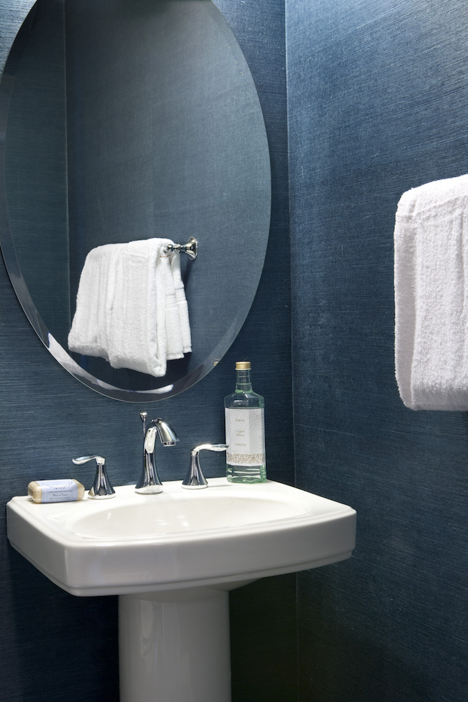 blue bathroom with white sink and oval mirror