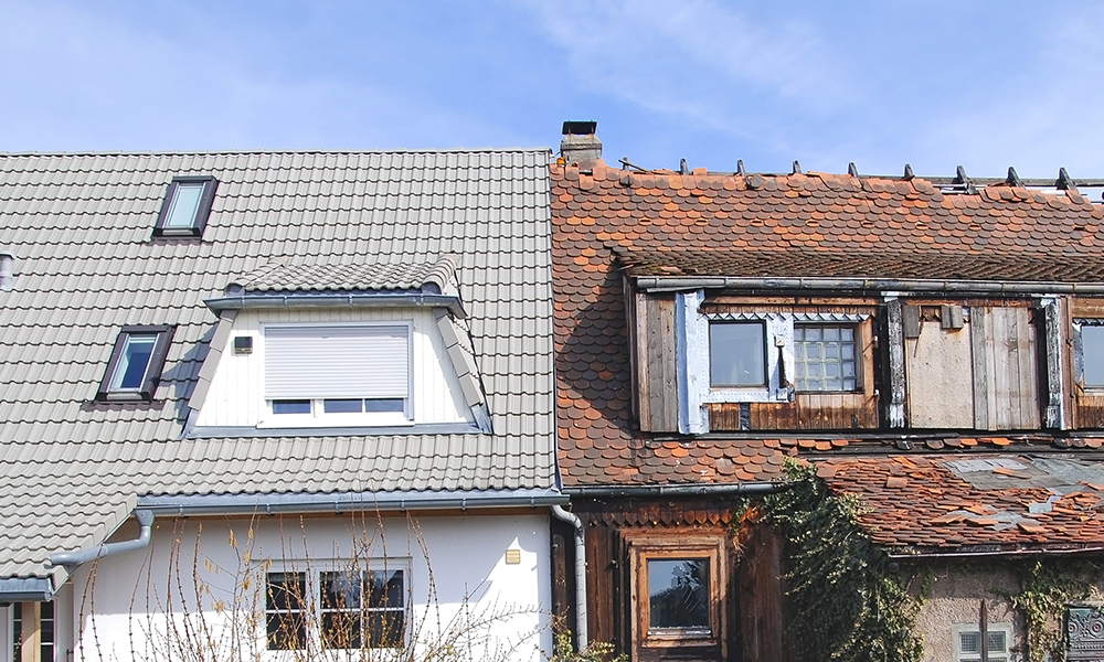 A dilapidated house sits beside a well-kept house.