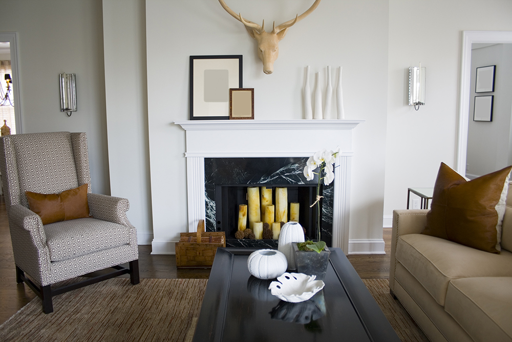 Chic neutral living room with white walls and beige furniture. The white fireplace is filled with 8 beige pillar candles.