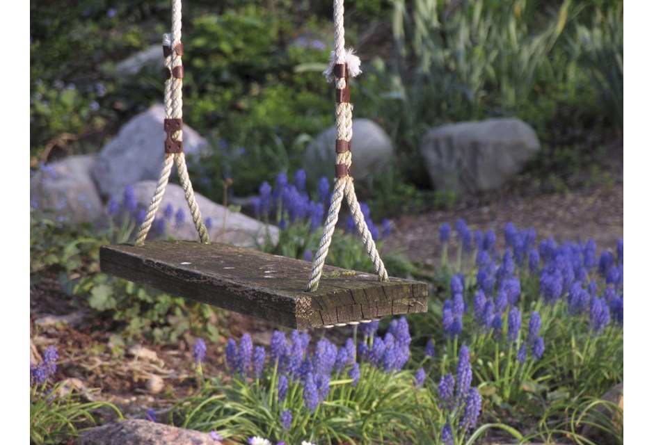 A wooden, rustic backyard swing in the garden