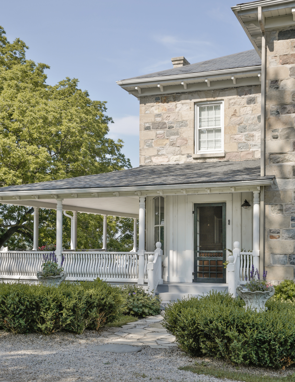 A converted farmhouse with wrap-around porch and stone walkway