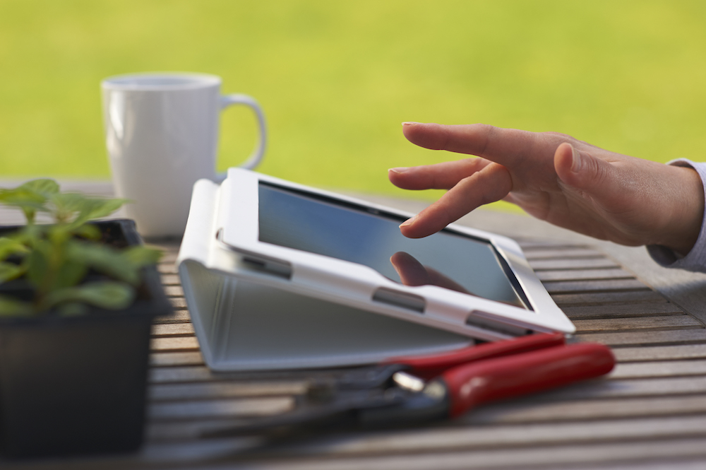 Tablet on wood table with garden in background