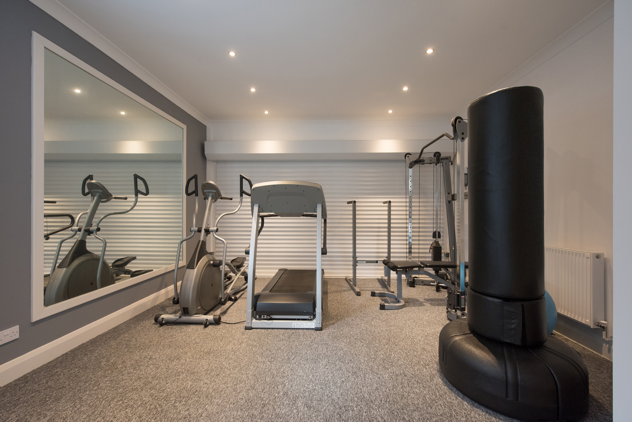 Home gym with grey floor and big mirror