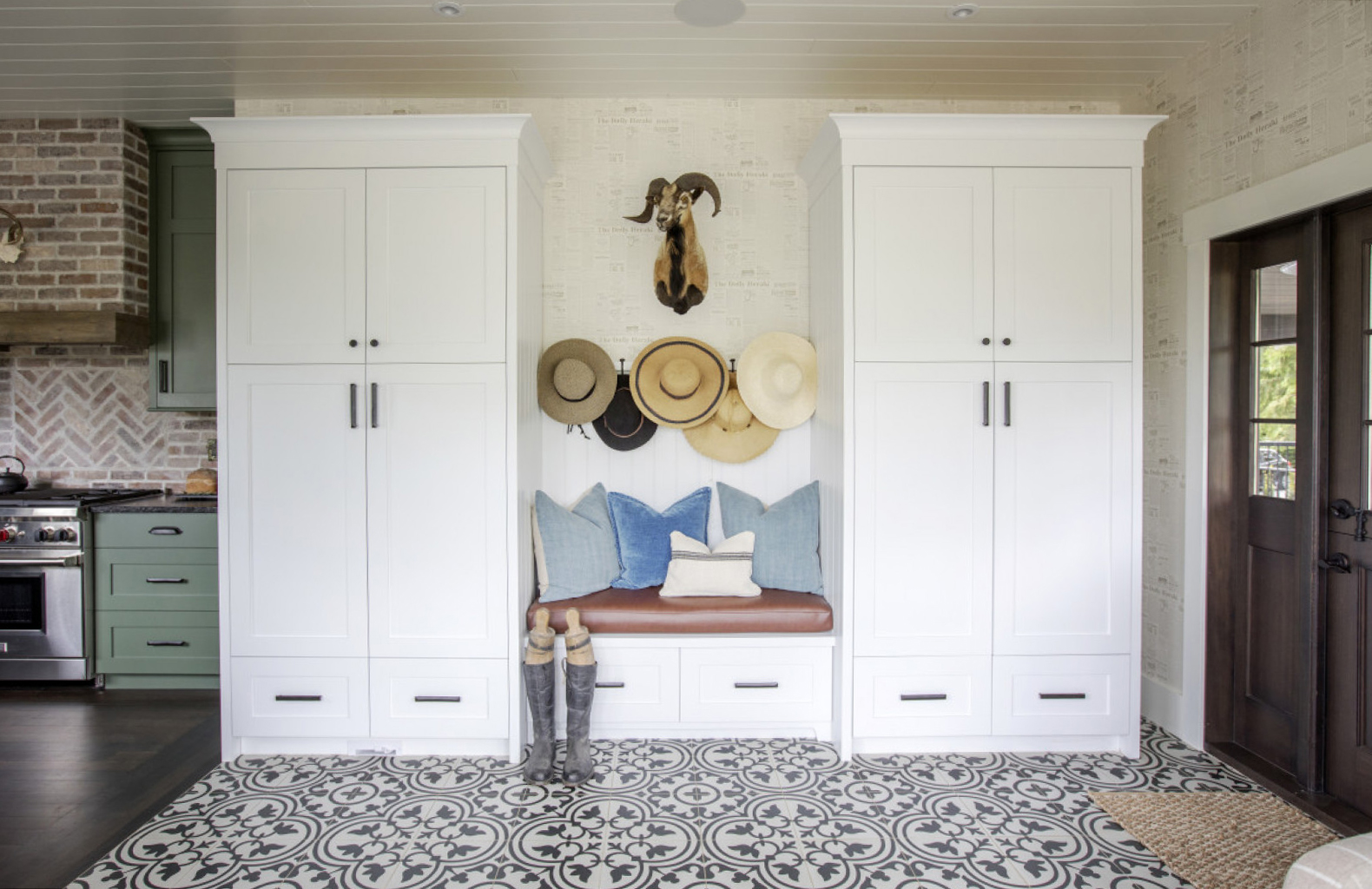 Mudroom, bench flanked by white cabinets, black and white patterned tile floor