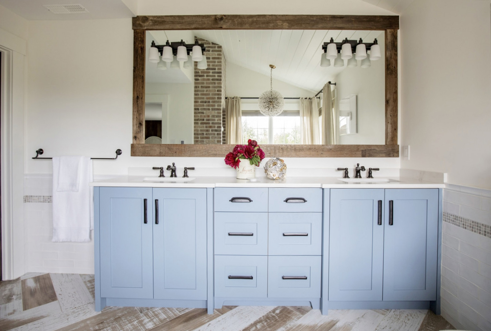 double sink vanity, blue cabinets, black hardware, red flower arrangement