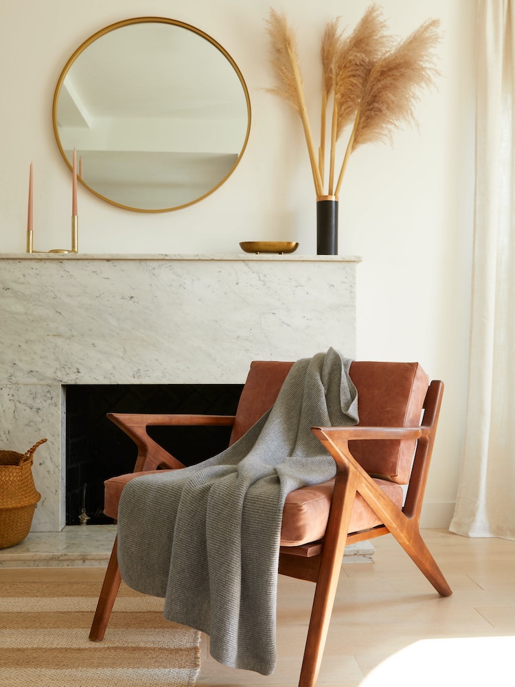 minimal white living room with marble fireplace and wooden chair