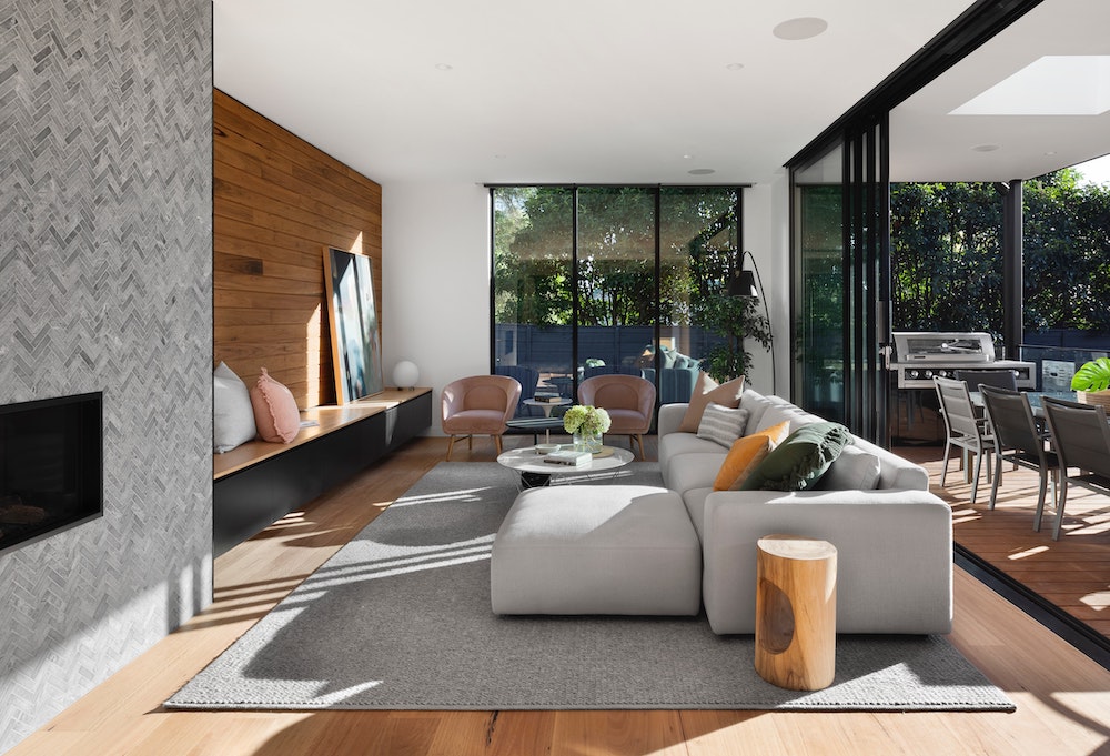 spacious living room with grey area rug and couch with pops of yellow, green and pink pillows