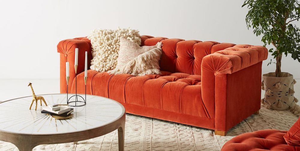 A tufted velvet orange-red sofa from Anthropoligie