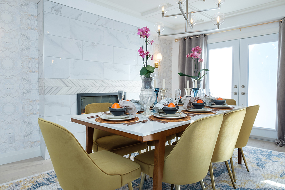 Dining room table with gold chairs around it. Two orchids sit in vases on top of the table.