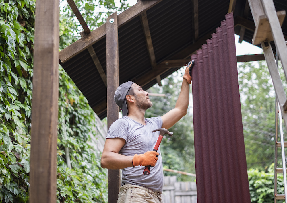 Man building roof and holding roof material onduline.