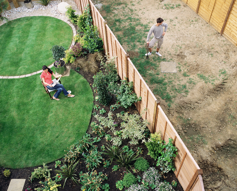 Neighbours in their gardens with fence between them