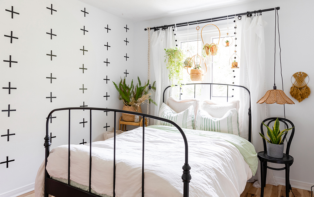 boho white bedroom with row of hanging green plants above bed