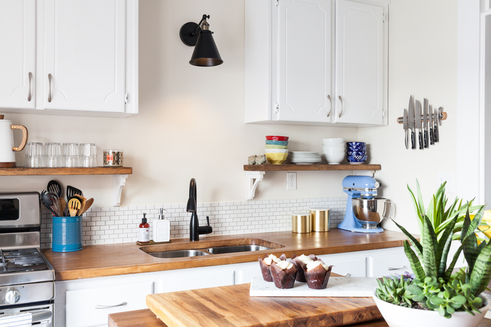 A small kitchen space with wooden counters, appliances and a magnetic knife strip mounted on the wall