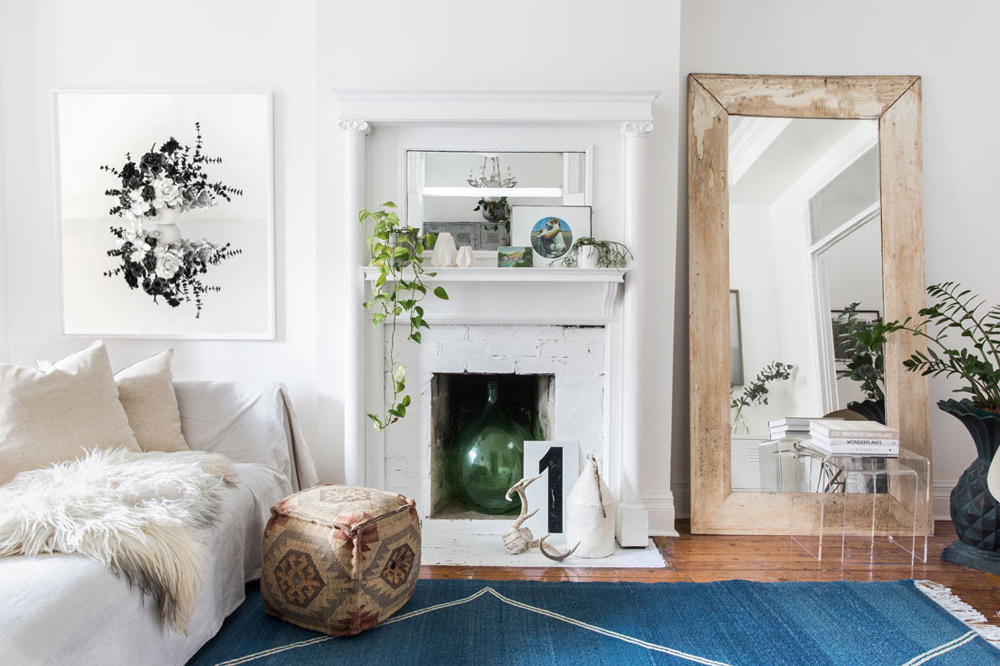 White living room with old brick fireplace and large wood mirror