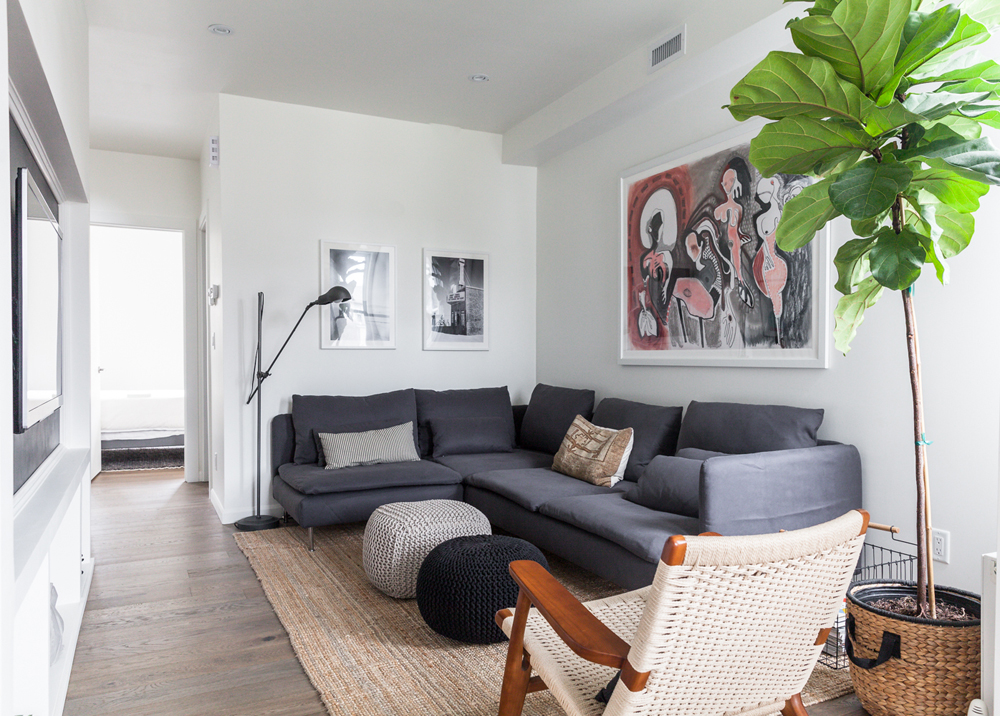 A neutrally coloured living room with dark furniture in a small space