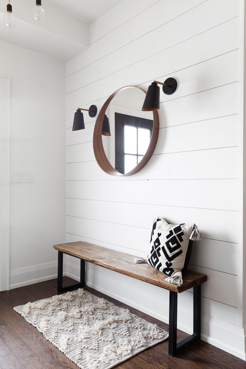 Modern entryway with flanking sconces, an IKEA mirror, a bench and a rug.