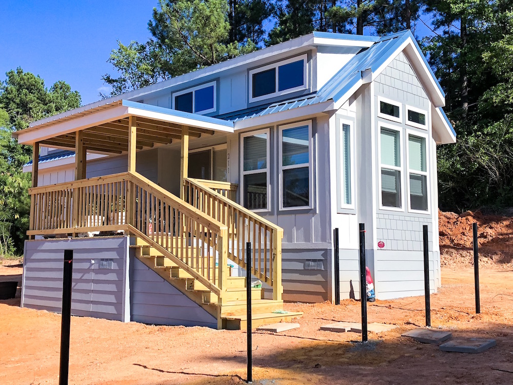 blue tiny house with porch out in the country