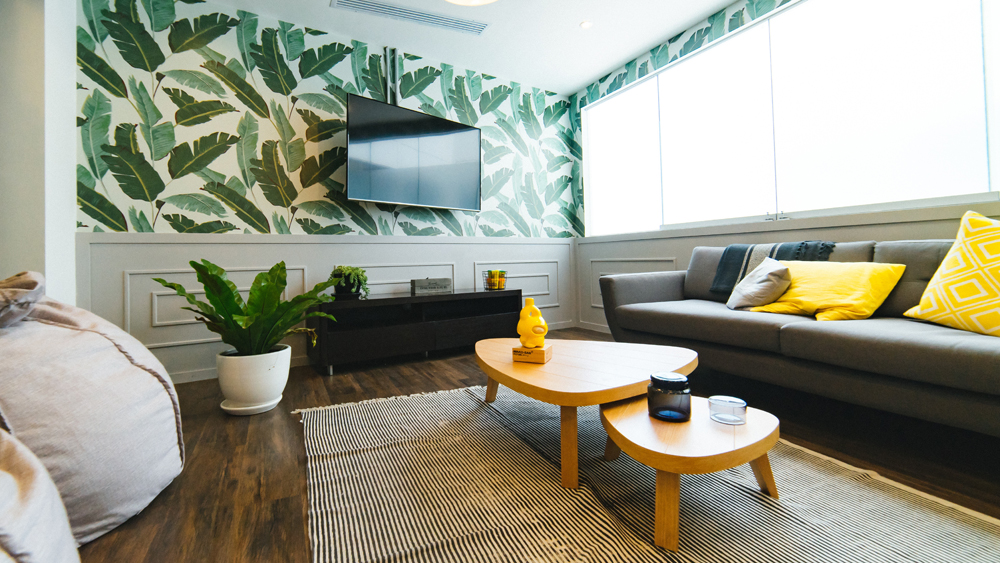 Colourful living room with green tropical-print wallpaper.