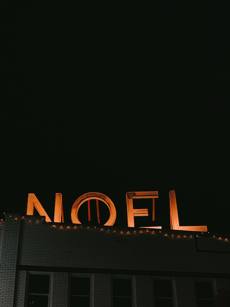 brick building with NOEL rooftop decoration and string lights