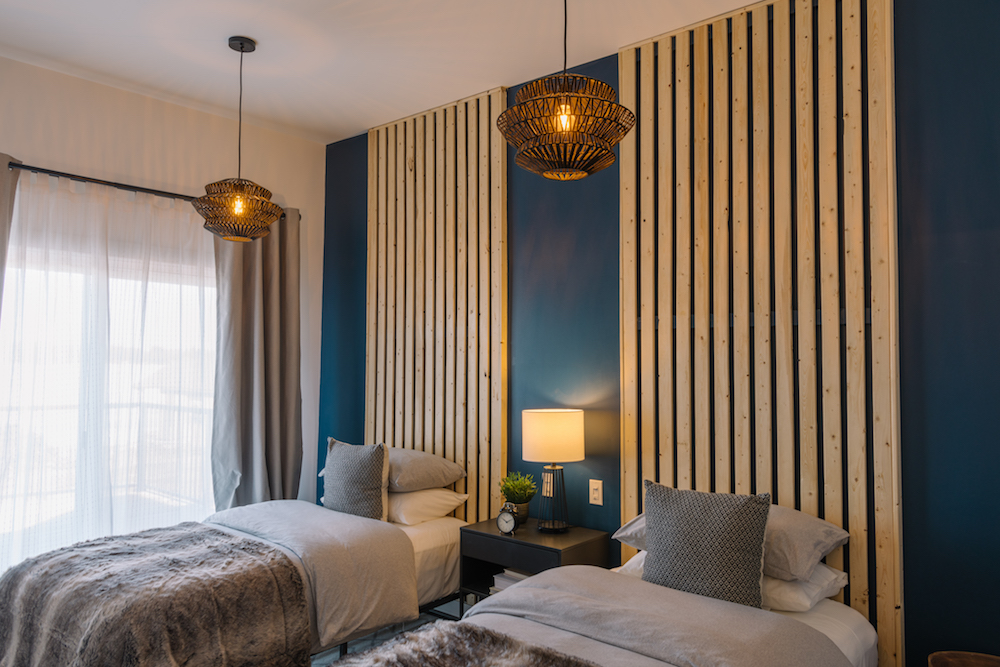 Double beds in bedroom with dark blue and wood accent wall