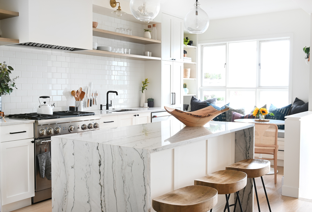 Natural Touches A white kitchen with a waterfall island (with heavy veining) and wood-topped stools
