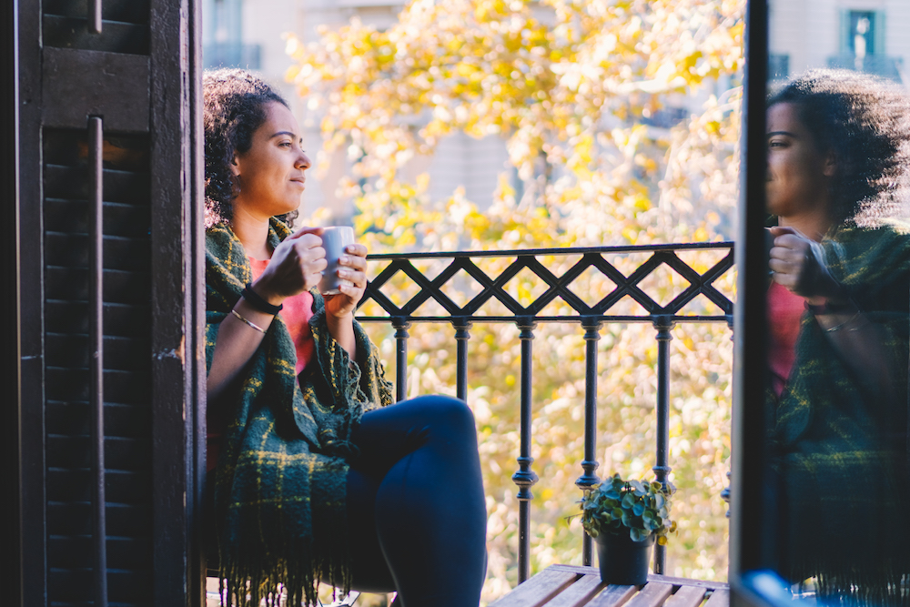 woman with plaid blanket on balcony