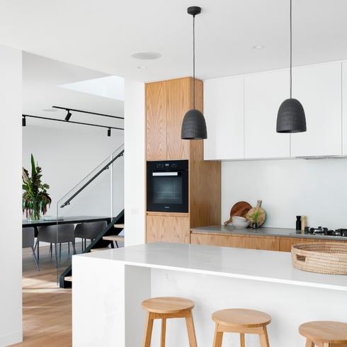 A modern kitchen with sleek high-end finishes and black pendant lights