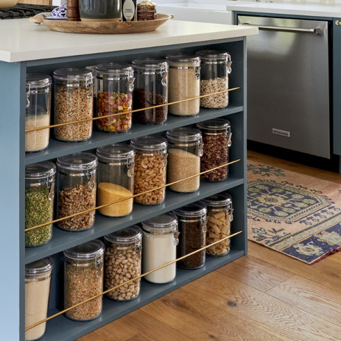 A blue painted island with an open pantry with glass jars