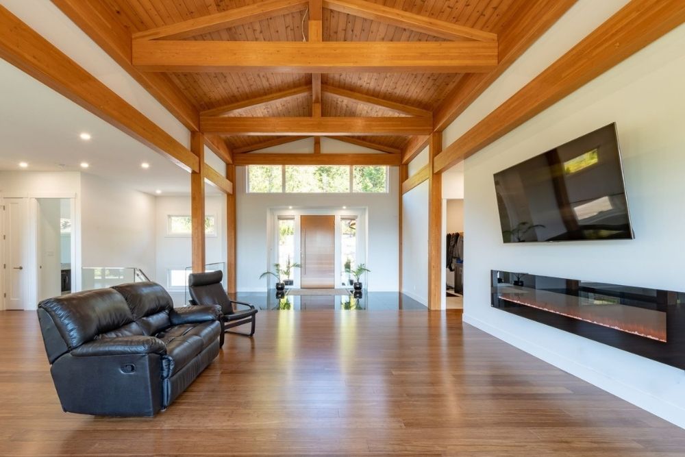 A minimalist entryway with a sleek fireplace, a TV mounted on the wall, white walls and black chairs.