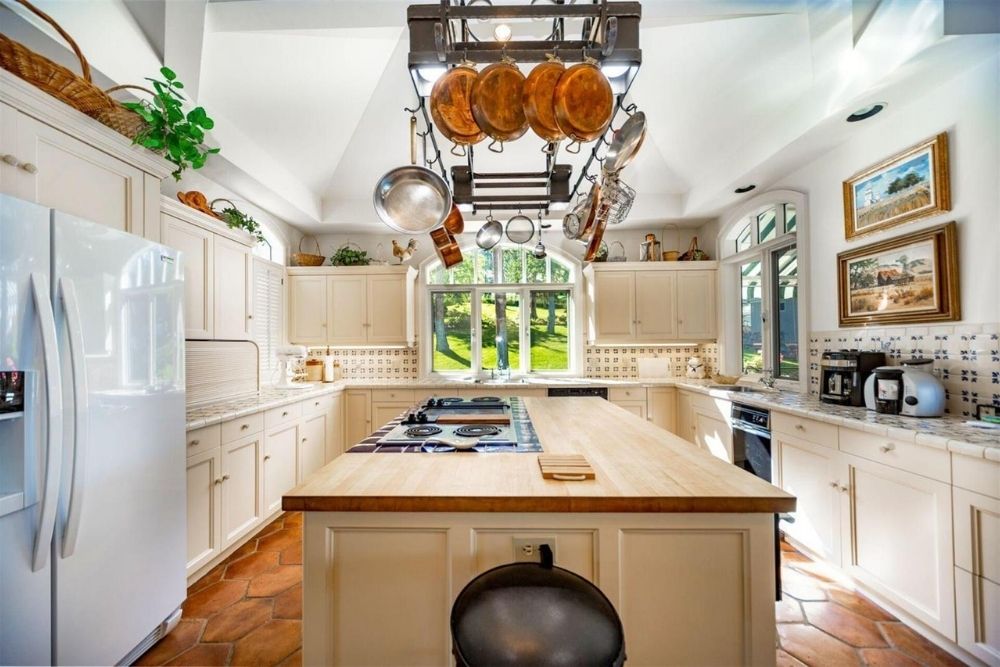 A gorgeous small cozy kitchen with white cabinets and a white kitchen island in this luxe Canadian cottage.