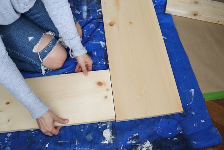 Courtney building the face of her DIY fireplace out of wood planks.