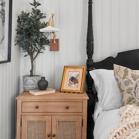 Primary bedroom nightstand with picture frame and plant.