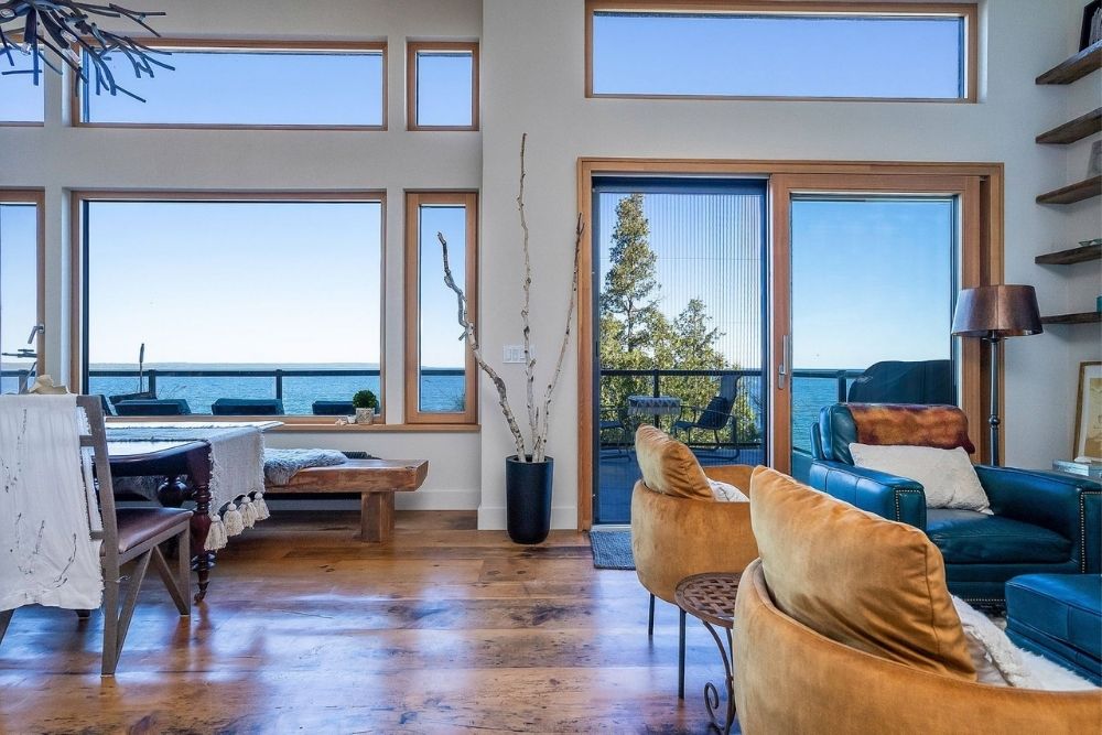 A living and dining room with big bright windows overlooking the lake.