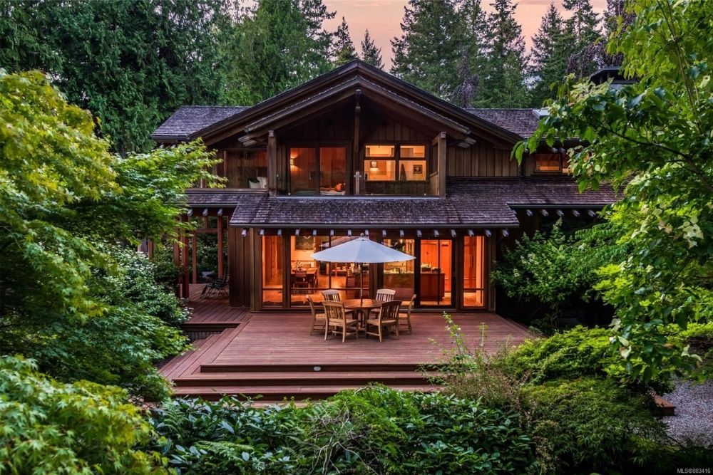 A luxe yet cozy wooden cottage with an outdoor patio and spacious deck, surrounded by trees in Western Canada.