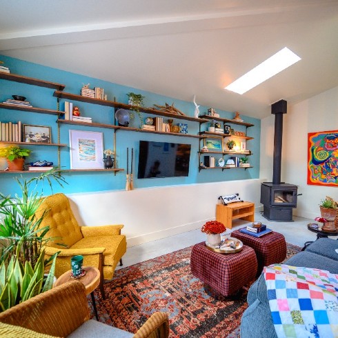 Living room with bright blue accent wall, skylight and wood-burning fireplace