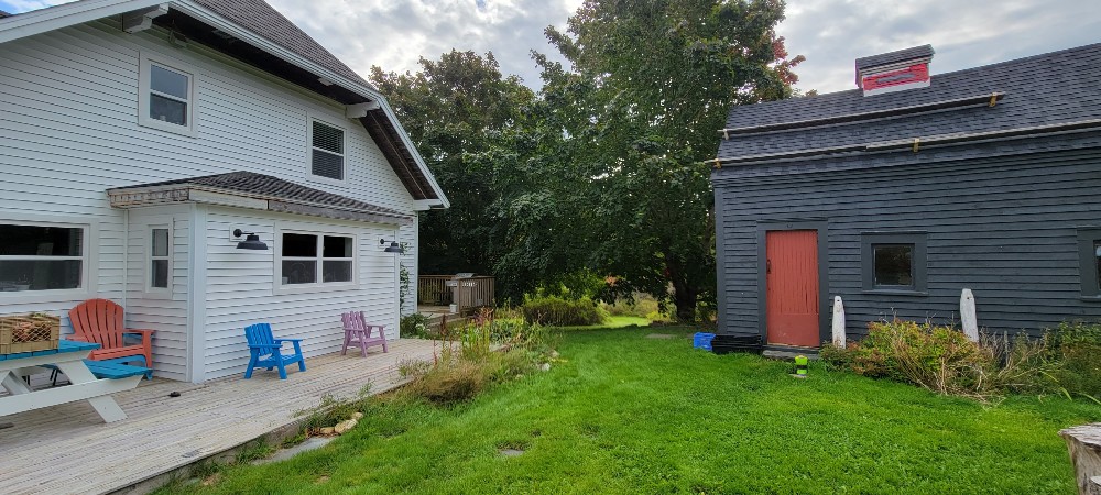 Randy's house with white siding and an old deck