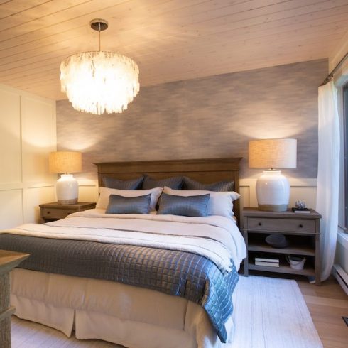 Primary bedroom in cottage rental with a blue feature wall and white and grey bedding