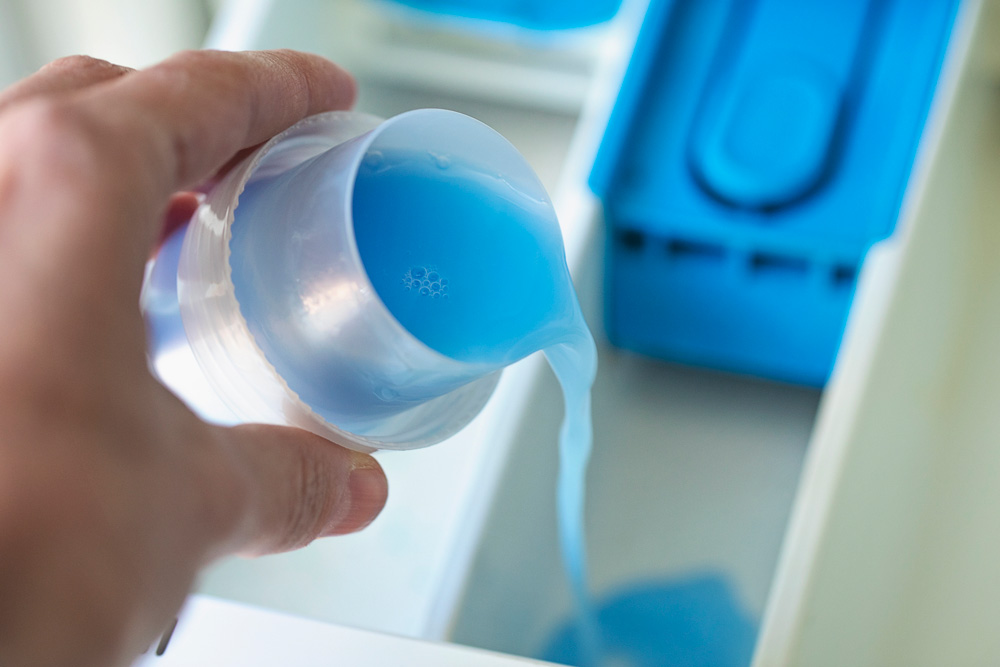 Pouring fabric softener into washing machine