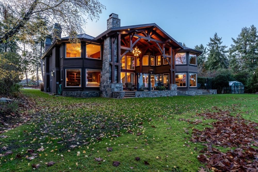 The back of the house of a luxury property with a big backyard and outdoor chandelier.