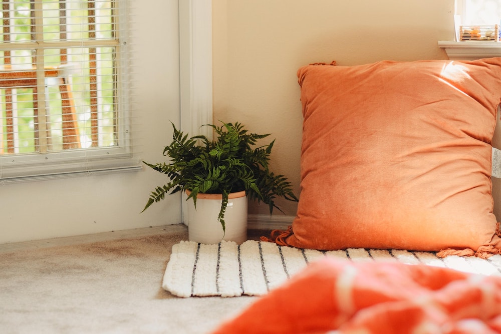 orange floor pillow and white rug