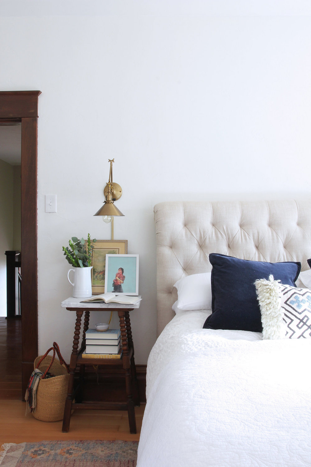 A country farmhouse bedroom showing a stool as a nightstand