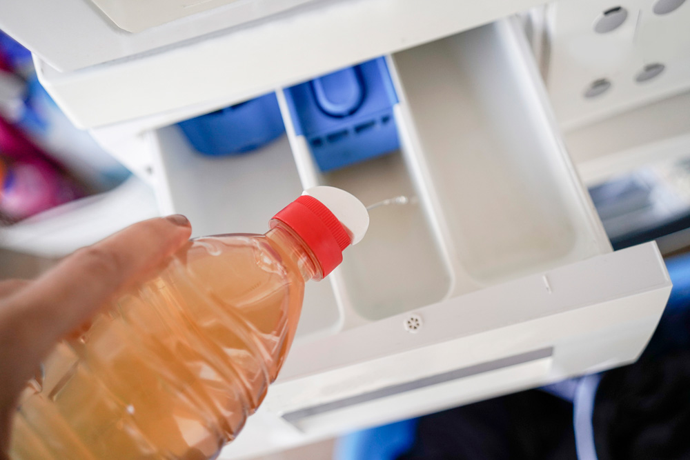 Pouring vinegar into a washing machine