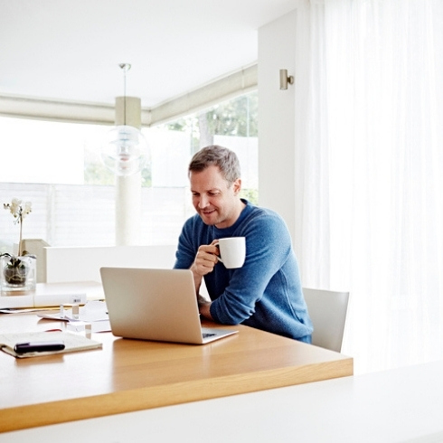 TitleMan working at home using laptop drinking coffee