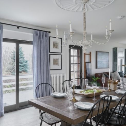 A grey painted dining room with a wooden dining table and black chairs