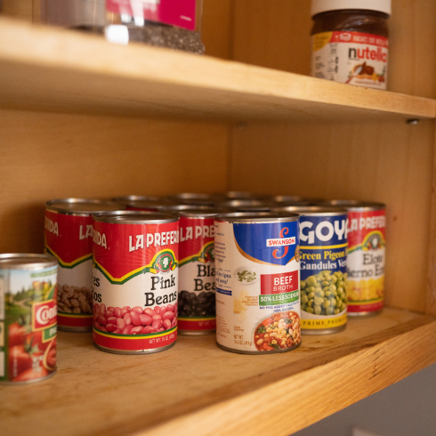 Various canned goods stacked inside a cabinet.